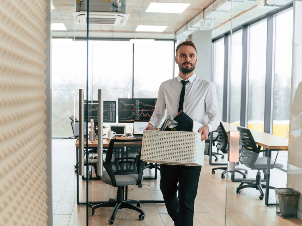 Empleado saliendo de la oficina con caja de pertenencias personales tras desvinculación laboral, ilustrando el costo de rotación de personal en empresa moderna