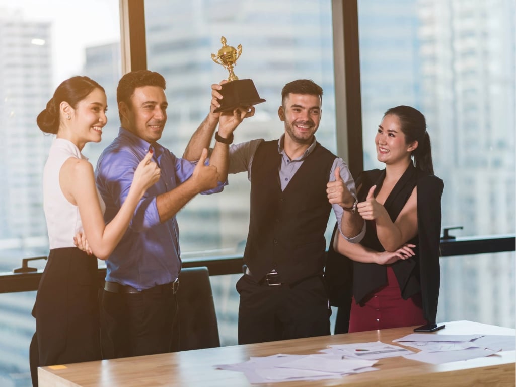 Equipo de trabajo celebrando un logro en la oficina, reflejando una cultura del reconocimiento que fortalece la motivación y el compromiso de los colaboradores.