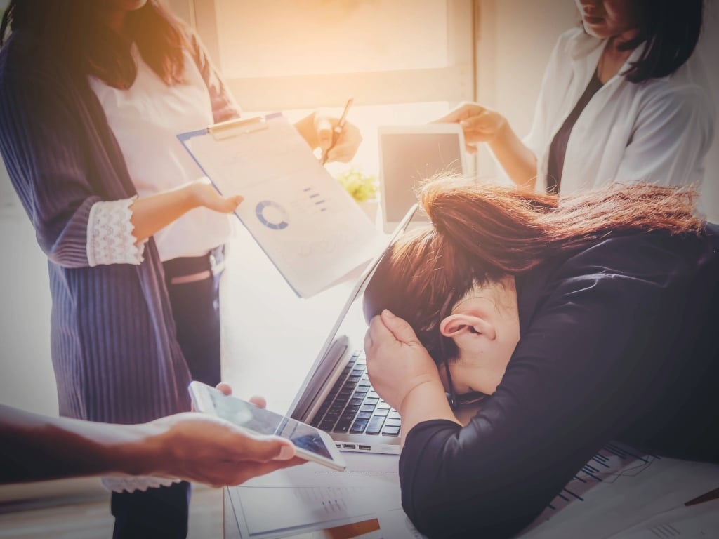 Mujeres tomándose la cabeza con las manos, mostrando los riesgos psicosociales en el trabajo. 